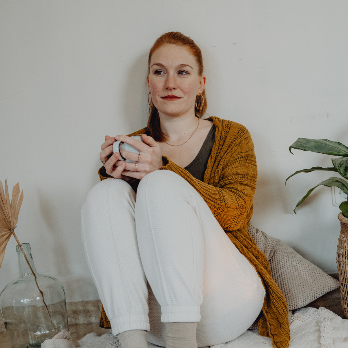 Eine Frau hält eine Tasse Tee und schaut gedankenverloren ins Leere.